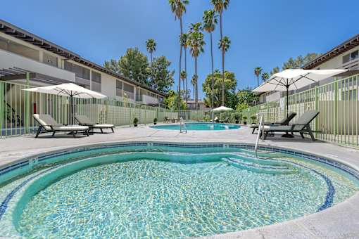 A pool surrounded by palm trees and sun loungers.