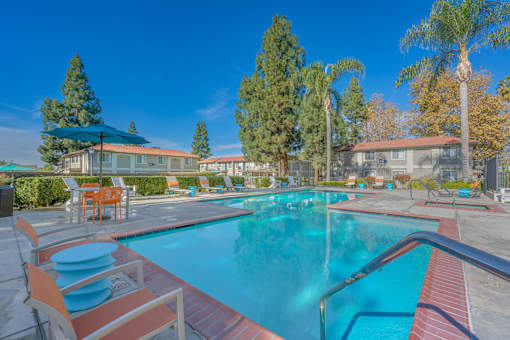 A swimming pool surrounded by orange chairs and trees.