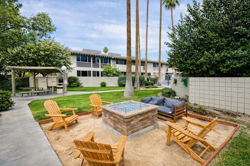 A backyard with a fire pit and chairs.