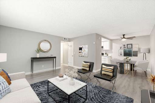 A living room with a white couch, a coffee table, and a mirror on the wall.