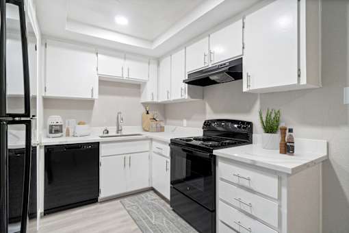 A modern kitchen with black appliances and white cabinets.