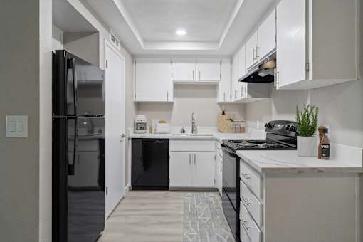 A modern kitchen with white cabinets and black appliances.