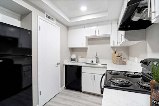 A modern kitchen with black appliances and white cabinets.