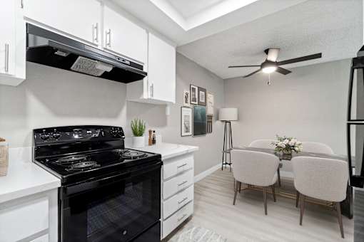 A black stove in a white kitchen with a fan.