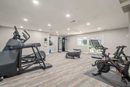 A spacious gym with a variety of exercise equipment including treadmills, stationary bikes, and a rowing machine.