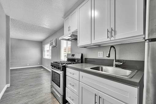 A kitchen with a stove, sink, and cabinets.