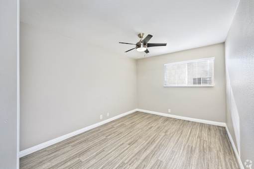 A room with a ceiling fan and a window with blinds.
