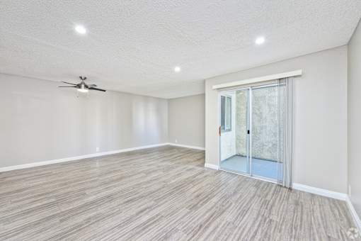 A room with a ceiling fan and sliding glass door.