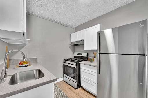 A modern kitchen with a stainless steel refrigerator, sink, and stove.