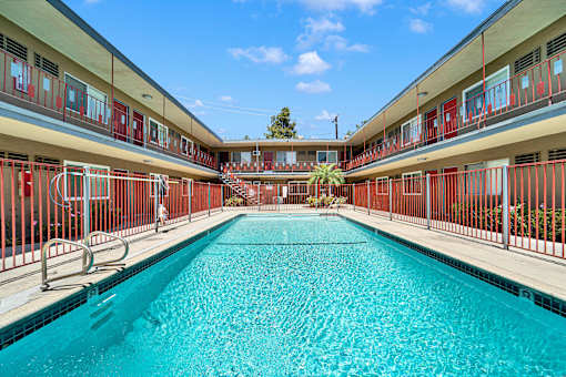 A long rectangular pool in a building with red railings.