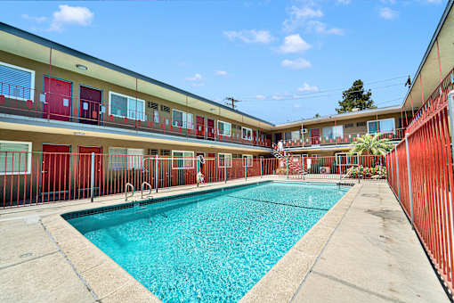 A swimming pool in front of a building with red doors.