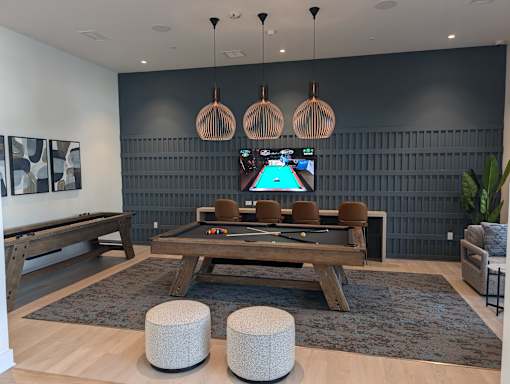 A room with a pool table and a TV mounted on the wall.