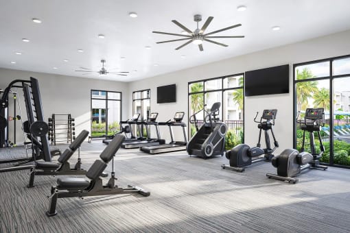 a gym with cardio equipment and windows in a building