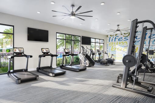 a gym with cardio equipment and windows in a building