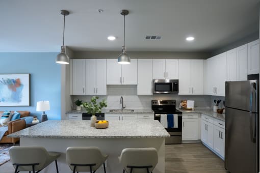 a kitchen with white cabinets and a marble counter top