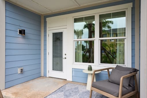 a chair and a table on a porch next to a door