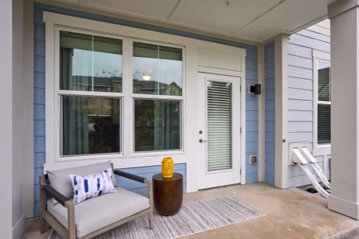 a front porch with a chair and a yellow vase on it