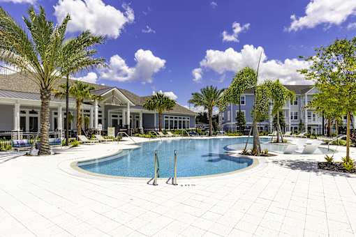 A swimming pool surrounded by palm trees and a white tiled patio.