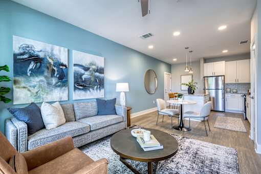 A living room with a grey couch, a coffee table, and a painting on the wall.