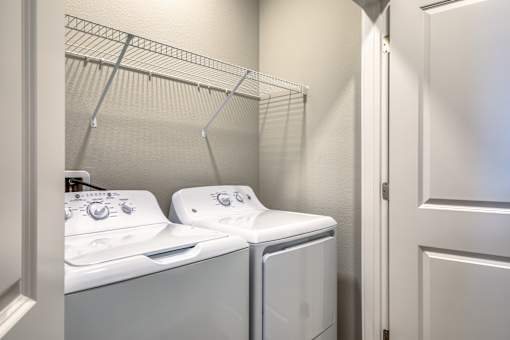 Two white washing machines in a laundry room.
