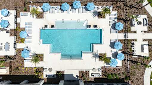 An aerial view of a swimming pool surrounded by lounge chairs and umbrellas.