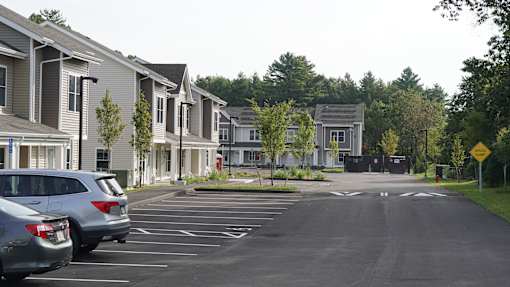 A parking lot in front of a residential area with cars parked.