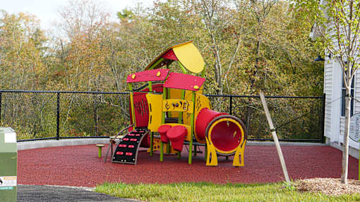 A playground with a red and yellow slide.