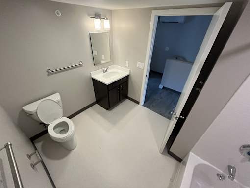 A bathroom with a toilet, sink, mirror, and a shower.