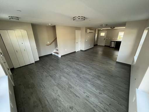 A large empty room with wooden floors and white walls.