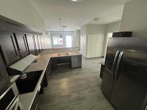 A kitchen with a black refrigerator and a black stove top oven.