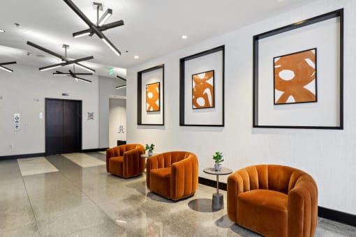 a lobby with orange chairs and pictures on the wall
