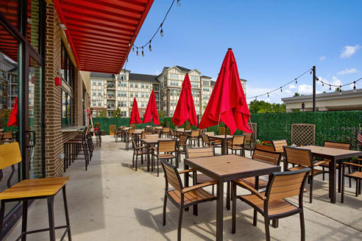 a patio with tables and chairs and red umbrellas