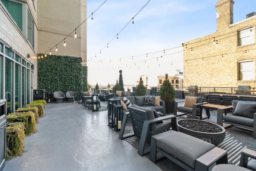 a rooftop patio with chairs and tables and a fire pit