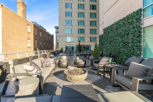 a rooftop patio with couches and chairs and a fire pit