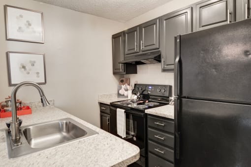 a kitchen with black appliances and white granite countertops at Hamilton at Kings Place, Maryland, 21046