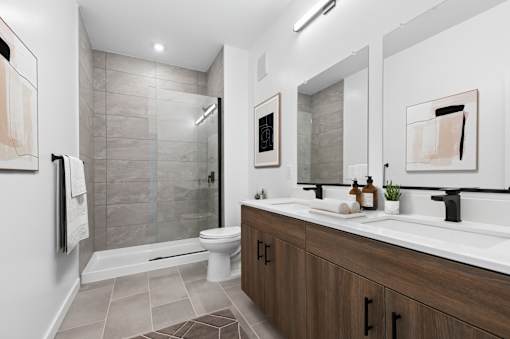 A modern bathroom with a walk-in shower and double sinks.
