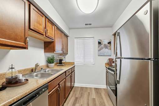 A kitchen with wooden cabinets and a stainless steel refrigerator at Poplar Glen Apartments, Columbia, MD, 21044.