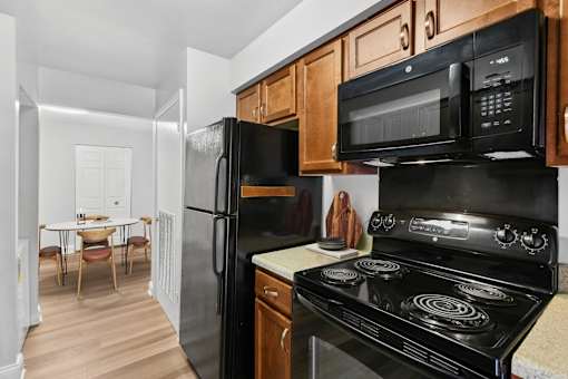 A black stove top oven sits under a microwave in a kitchen  at Poplar Glen Apartments, Columbia, MD, 21044.