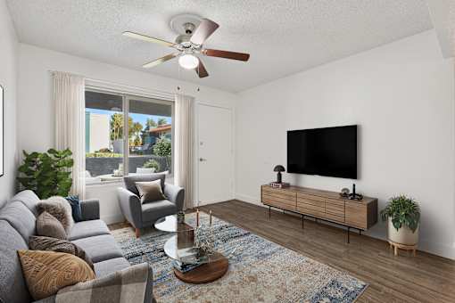 A living room with a grey sofa, a wooden coffee table, a flat screen TV, and a ceiling fan at Riviera Park, Chandler Arizona