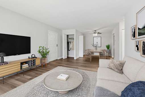 A living room with a white couch and a flat screen TV at Poplar Glen Apartments, Columbia, MD, 21044.