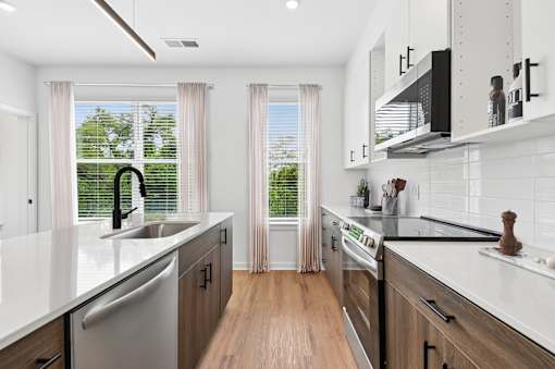 A modern kitchen with white countertops and wooden floors.