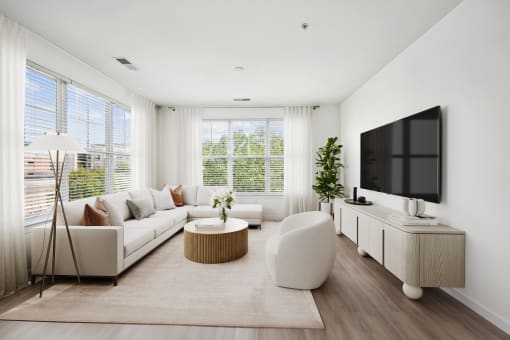 A modern living room with a white sofa, a round coffee table, and a flat-screen TV at Aspire Apollo, Camp Springs, MD