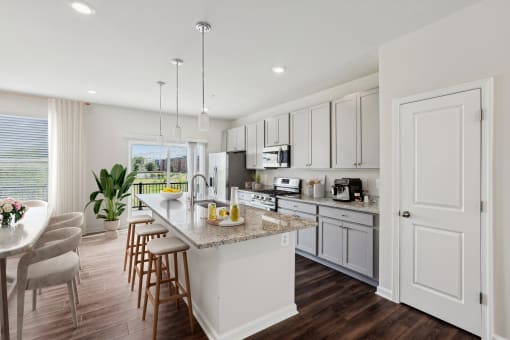 an open kitchen and dining room with white cabinets and a marble counter top at Refinery Row, Baltimore, 21224