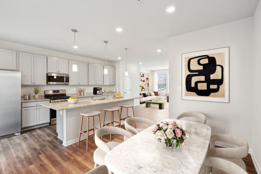 an open kitchen and dining room with white cabinets and a marble table at Refinery Row, Baltimore, MD 21224