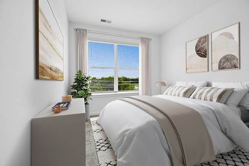 A bedroom with a large bed and a window overlooking a green landscape.