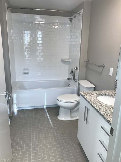 A white toilet sits next to a walk-in shower in a bathroom.