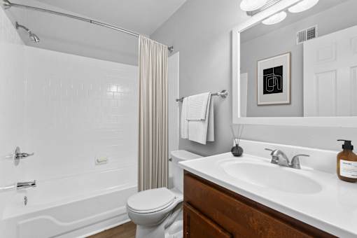 A white bathroom with a toilet, sink, and shower  at Poplar Glen Apartments, Columbia, MD, 21044.