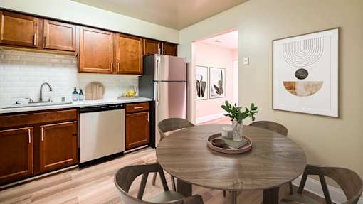 A kitchen with a table and chairs in the foreground and a framed picture on the wall at Poplar Glen Apartments, Columbia, MD, 21044.