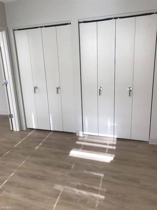 Three white cupboards with silver handles are in a room with a light-colored floor.