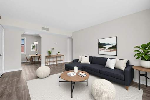 A living room with a black couch, a coffee table, and a large painting on the wall at Highland Ridge Apartments, Capitol Heights 20743